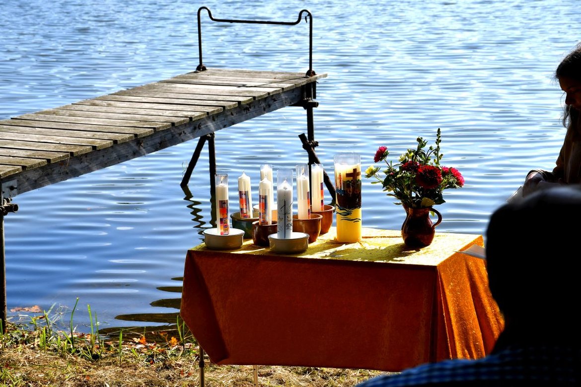 Holzsteg am See mit Tisch voller Taufkerzen